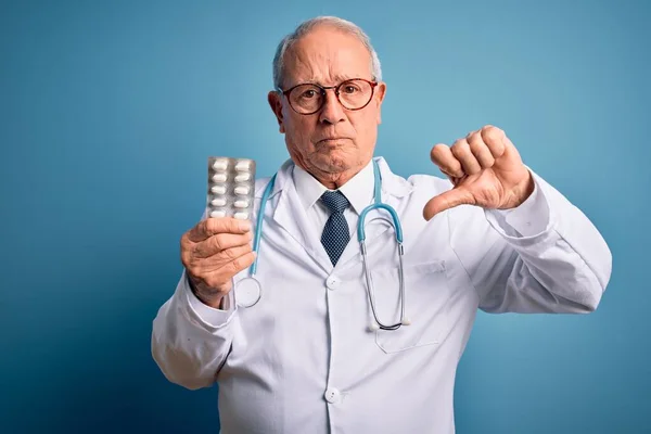 Starší Šedovlasý Lékař Drží Farmaceutické Pilulky Nad Modrým Pozadím Rozzlobeným — Stock fotografie