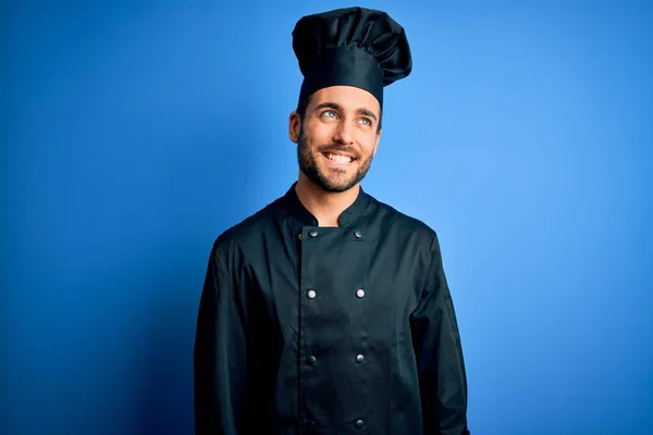年轻英俊的厨师 留着胡子 身穿炊具制服 头戴蓝色背景的帽子 面带微笑 神态自然 充满自信的笑 — 图库照片