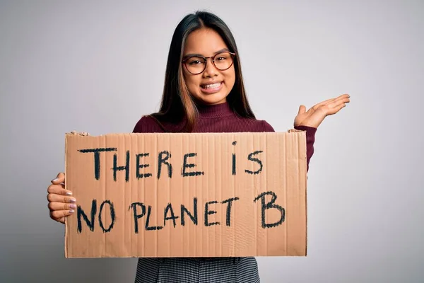 Young asian activist girl asking for environment holding banner with planet message very happy and excited, winner expression celebrating victory screaming with big smile and raised hands