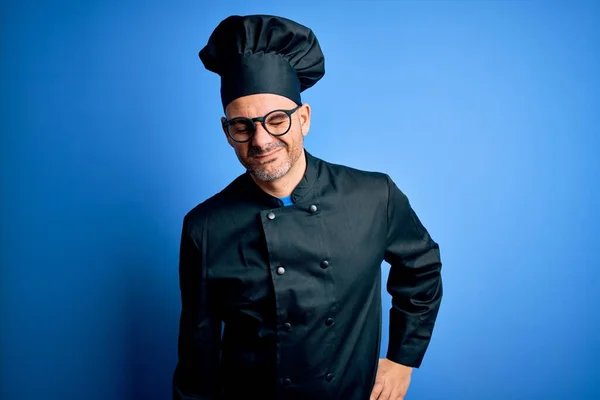 Young handsome chef man wearing cooker uniform and hat over isolated blue background Suffering of backache, touching back with hand, muscular pain