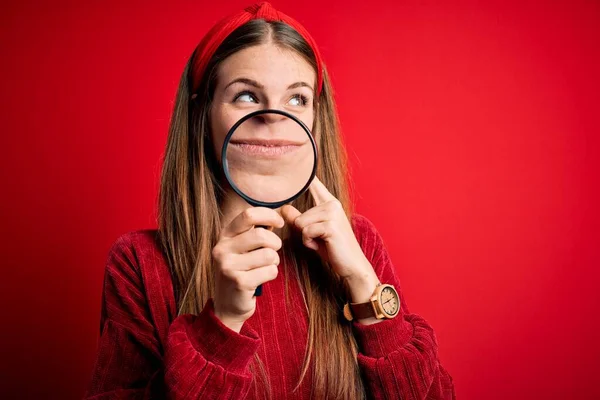 Jonge Mooie Roodharige Detective Vrouw Met Vergrootglas Geïsoleerde Rode Achtergrond — Stockfoto