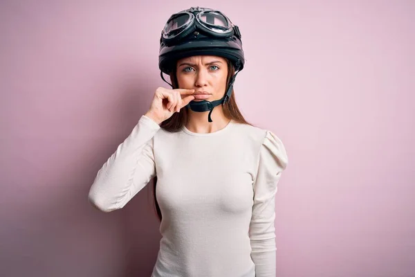 ピンクの背景の口と唇の上に元ヘルメットを身に着けて青い目を持つ若い美しいオートバイの女性は指でジップとしてシャットダウンします 秘密裏に黙ってタブーを語る — ストック写真