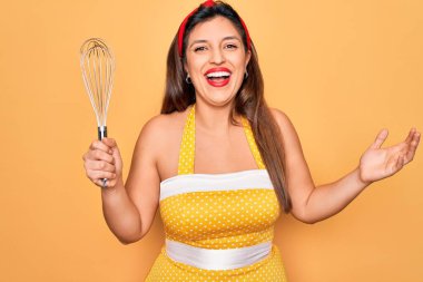 50 'li yaşların modasında seksi giyinen genç Latin kadın çırpıcı tutuyor çok mutlu ve heyecanlı, kazanan yüz ifadesi zaferi kutluyor büyük bir gülümsemeyle ve el kaldırarak.