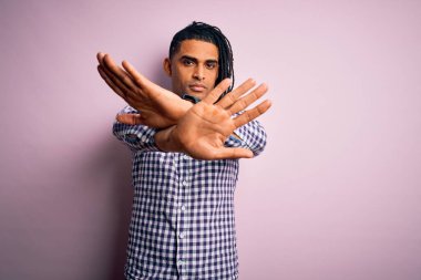 Rastgele gömlek giyen Afro-Amerikan genç, yakışıklı Afro-adam. Kollarını kavuşturup, avuç içlerini ters çeviren, kızgın yüzlü.