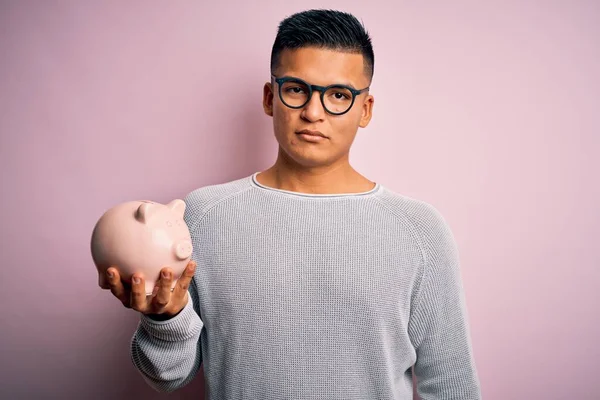 Jovem Bonito Latino Homem Segurando Porquinho Banco Sobre Isolado Fundo — Fotografia de Stock