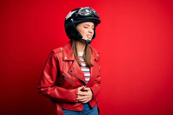 若い美しいブルネットのオートバイのヘルメットと胃の上に手で赤いジャケットを身に着けているオートバイの女性は吐き気 痛みを伴う病気が体調を崩します アチェの概念 — ストック写真