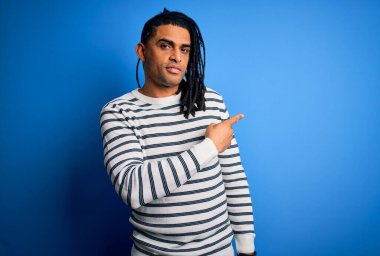 Rastgele çizgili süveter giyen Afro-Amerikan genç, yakışıklı Afro-adam. Elinle işaret ederek reklamını yapıyor. Ciddi ve sakin bir yüzü var.