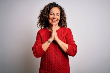 Orta yaşlı esmer kadın, günlük süveter giyer, izole edilmiş beyaz arka planda durur, birlikte dua eder, af diler, kendinden emin bir şekilde gülümserdi..