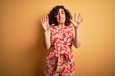 Genç, güzel, kıvırcık Arap kadın tatilde. Çiçekli bir elbise ve güneş gözlüğü takıyor. Korkudan ödü patlıyor. Panik konsepti.