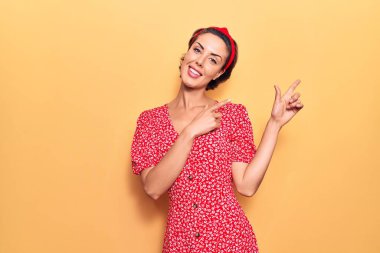 Genç ve güzel bir kadın gündelik elbiseler giyiyor ve Diadem gülümsüyor ve kameraya bakıyor iki eliyle ve parmaklarıyla kenarı işaret ediyor.. 