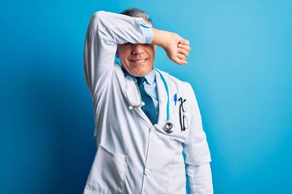 中年英俊 白发苍苍的医生 身穿外套 用蓝色听诊器蒙住眼睛 胳膊上挂着微笑 笑容满面 笑容满面 盲目概念 — 图库照片