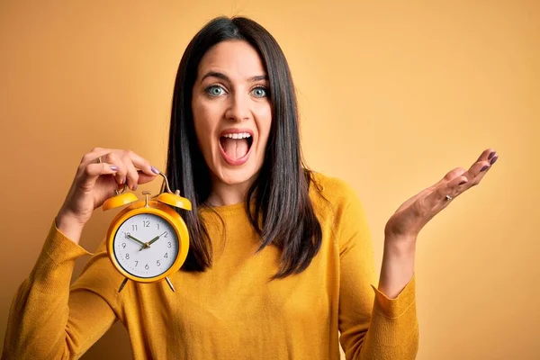 Jonge Vrouw Met Blauwe Ogen Houden Wekker Staande Geïsoleerde Gele — Stockfoto