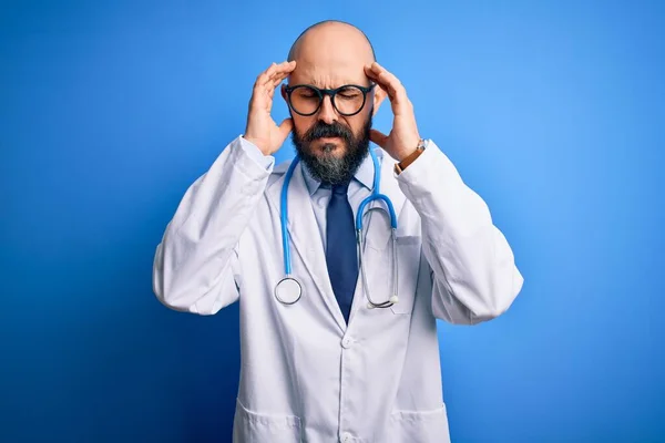 英俊的秃头医生 留着胡子 戴着眼镜和听诊器 背带蓝色背景 手部因压力头疼 痛苦的偏头痛 — 图库照片