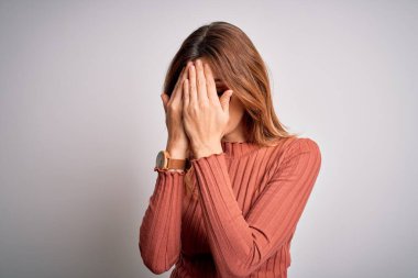 Genç, güzel, esmer bir kadın beyaz arka plan üzerine gözlük takıyor ve ağlarken yüzünü ellerle kapatan üzgün bir ifade takınıyor. Depresyon kavramı.