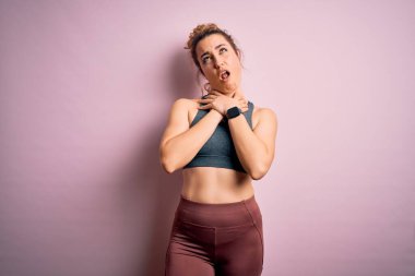 Genç ve güzel sarışın sporcu kadın spor yapıyor. Pembe arka planda spor giysisi giyip boğularak ölme diye bağırıyor. Sağlık problemi. Boğulma ve intihar konsepti.