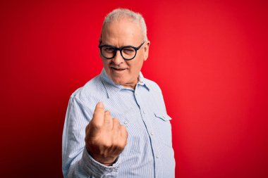 Orta yaşlı, yakışıklı, beyaz, sıradan çizgili gömlek ve gözlüklü, kırmızı arka planda bir adam. Buraya gel ve mutlu bir şekilde karşıla ve gülümse.