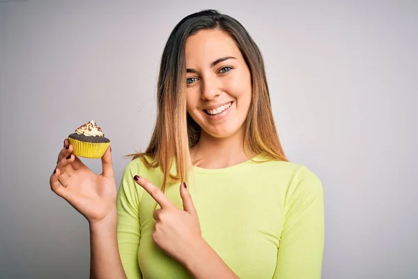 若いです美しいです女性とともに青い目食べる甘いチョコレートカップケーキ上白い背景非常に幸せなポインティングとともに手と指 — ストック写真