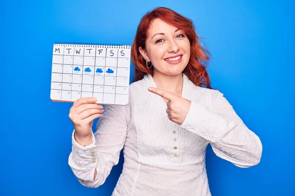 Jovem Ruiva Segurando Calendário Meteorológico Mostrando Semana Chuvosa Sobre Fundo — Fotografia de Stock