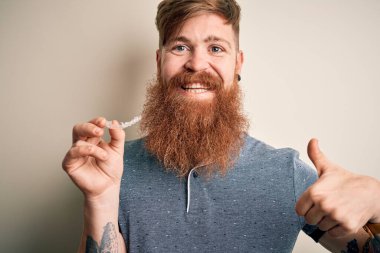 Dişlerinin düzeltilmesi için dişlerini sakallı, kızıl saçlı İrlandalı bir adam. Kocaman gülümsüyor. Tamam işareti yapıyor.