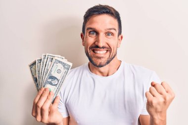 Soyutlanmış beyaz arka planda bir deste para tutan yakışıklı genç adam gururla haykırıyor, zaferi ve başarıyı kutluyor.