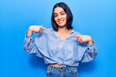 Genç, güzel, latin bir kadın, günlük kıyafetler giyiyor, kendine güveniyor, gülümsüyor, kendini gururlu ve mutlu bir şekilde gösteriyor.. 