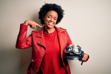 Kıvırcık saçlı, motosiklet kaskı takan, kendine güvenen, gülümseyen, kendini gururlu ve mutlu gösteren Afro-Amerikan motosikletli genç bir kadın..