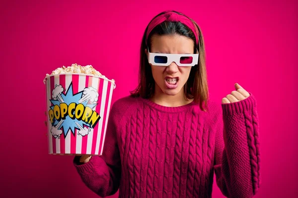 3Dメガネで映画を見ている若い美少女は怒りと怒りで叫んでいる間に怒りと怒りの拳を上げる怒っていると怒っているポップコーンとボックスを食べています 激怒と積極的な概念 — ストック写真