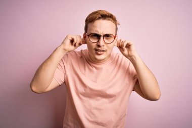 Genç, yakışıklı, günlük tişört giyen, pembe arka planda dikilen, parmaklarıyla kulaklarını çeken, komik bir jest yapan bir adam. Seçme sorunu
