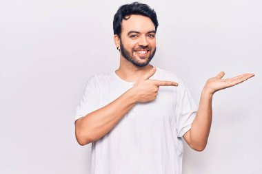 Gündelik kıyafetler giyen genç İspanyol adam kameraya hayret ediyor ve gülümsüyor.. 