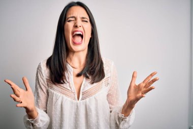 Mavi gözlü genç esmer kadın izole edilmiş beyaz arka plan üzerine gündelik tişört giyiyor. Deli gibi bağırıyor ve agresif bir ifade ve kolla bağırıyor. Hayal kırıklığı konsepti.