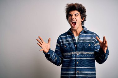 İzole edilmiş beyaz arka plan üzerinde duran genç ve yakışıklı bir adam çılgın ve sinirli bir şekilde bağırıyor ve agresif bir ifade ve kollarla bağırıyor. Hayal kırıklığı konsepti.