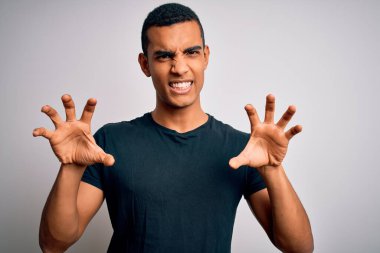 Genç, yakışıklı, Afro-Amerikalı bir adam beyaz arka planda dikilen günlük tişört giyiyor komik bir şekilde kedi gibi pençe hareketi yapıyor, agresif ve seksi bir ifade.