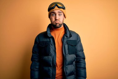 Kar giysileri ve kayak gözlüğü takan sakallı yakışıklı kayakçı komik suratlı yanakları şişiriyor. Havayla şişmiş ağız, çılgın bir ifade..