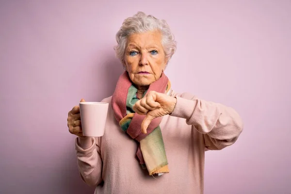 シニア美しい白髪の女性飲むマグカップのコーヒー隔離されたピンクの背景で怒りの顔 否定的な兆候を示す嫌いで親指ダウン 拒否の概念 — ストック写真