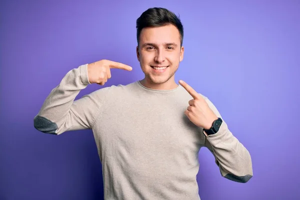 紫色の隔離された背景にカジュアルなセーターを着た若いハンサムな白人男性は 陽気な表情と指の歯と口で指して笑っています 歯科衛生の概念 — ストック写真