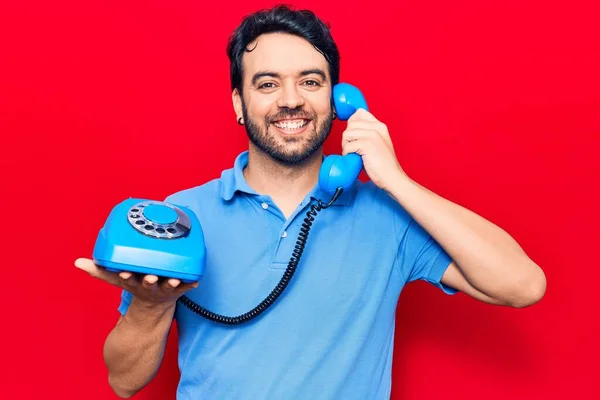 Joven Hombre Hispano Sosteniendo Teléfono Vintage Buscando Positivo Feliz Pie —  Fotos de Stock
