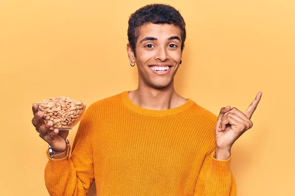 Young African Amercian Man Holding Peanuts Smiling Happy Pointing Hand — Stock Photo, Image