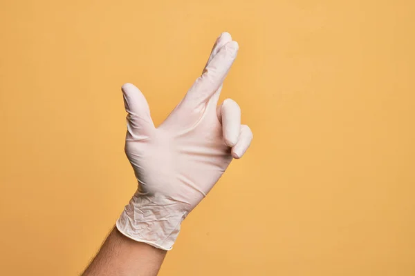 Mão Homem Jovem Caucasiano Com Luva Médica Sobre Fundo Amarelo — Fotografia de Stock