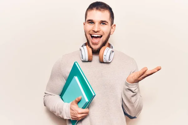 Jovem Homem Bonito Segurando Livro Usando Fones Ouvido Celebrando Realização — Fotografia de Stock