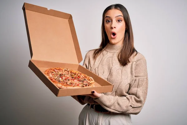 若いです美しいですブルネット女性保持ボックスとともにイタリアのピザ以上ホワイトバック怖がっていますでショックで驚きの顔 恐れと興奮で恐怖表現 — ストック写真