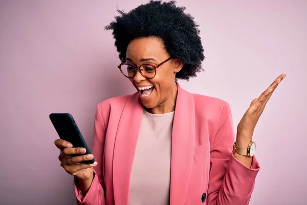 Young African American afro woman with curly hair having conversation using smartphone very happy and excited, winner expression celebrating victory screaming with big smile and raised hands