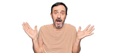 Orta yaşlı, çizgili tişört giyen yakışıklı bir adam izole edilmiş beyaz arka planda duruyor ve kolları açık, hiçbir fikri ve şüpheli bir yüzü yok..