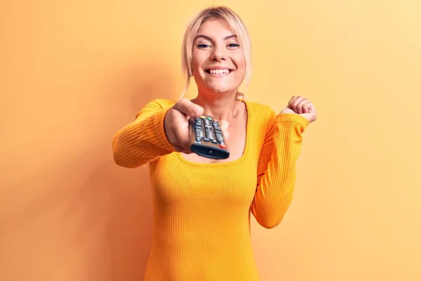 Blond Vrouw Veranderen Kanaal Met Behulp Van Televisie Afstandsbediening Gele — Stockfoto