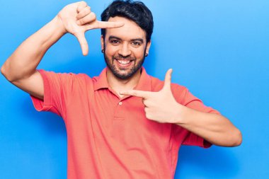 Gündelik kıyafetler giyen, gülümseyen, elleri ve parmakları gülen yüzlü, çerçeveli bir İspanyol. yaratıcılık ve fotoğrafçılık kavramı. 