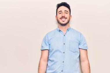 Yüzünde mutlu ve havalı bir gülümseme olan sıradan kıyafetler giyen genç İspanyol bir adam. şanslı kişi. 