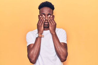 Genç Afro-Amerikan adam günlük kıyafetler giyiyor yorgunluk ve baş ağrısı için gözlerini ovuşturuyor, uykulu ve yorgun bir ifade takınıyor. görme sorunu 