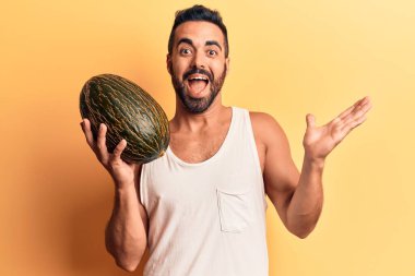 Karpuz tutan genç İspanyol adam başarıyı mutlu bir gülümsemeyle kutluyor ve kazanan el kaldırarak ifade ediyor. 