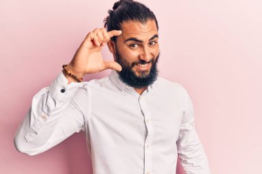 Gündelik kıyafetler giyen, gülümseyen, kendine güvenen, el hareketleriyle hareket eden, parmaklarıyla işaret yapan ve kameraya bakan genç bir Arap. ölçüm kavramı. 