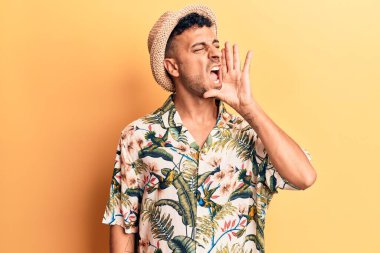 Yaz şapkası takan genç İspanyol adam el pençe divan bağırarak bağırıyor. iletişim konsepti. 