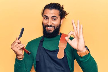 Önlük takan genç bir Arap berber ustura tutuyor. Parmaklarıyla imza atıyor, gülümsüyor. Mükemmel bir sembol. 